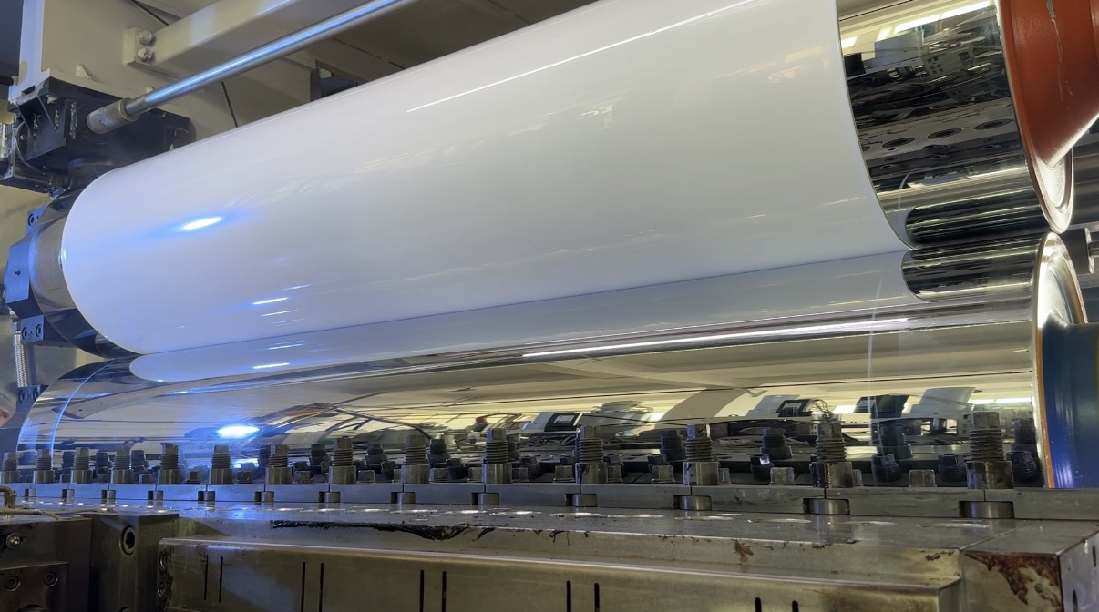 White sheet passing through forming rollers on the LYSHIRE extrusion line